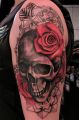 red rose on skull arm tattoo